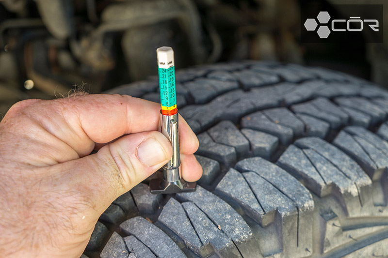 Using a tread wear gauge on a truck tire.